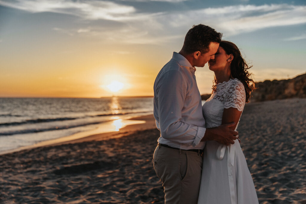 Coppia abbracciata in spiaggia al tramonto